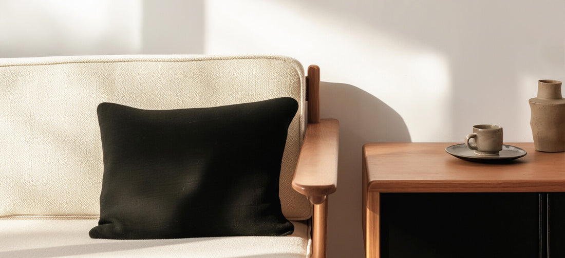 A cozy, minimalist scene featuring a beige textured sofa with a black cushion for contrast